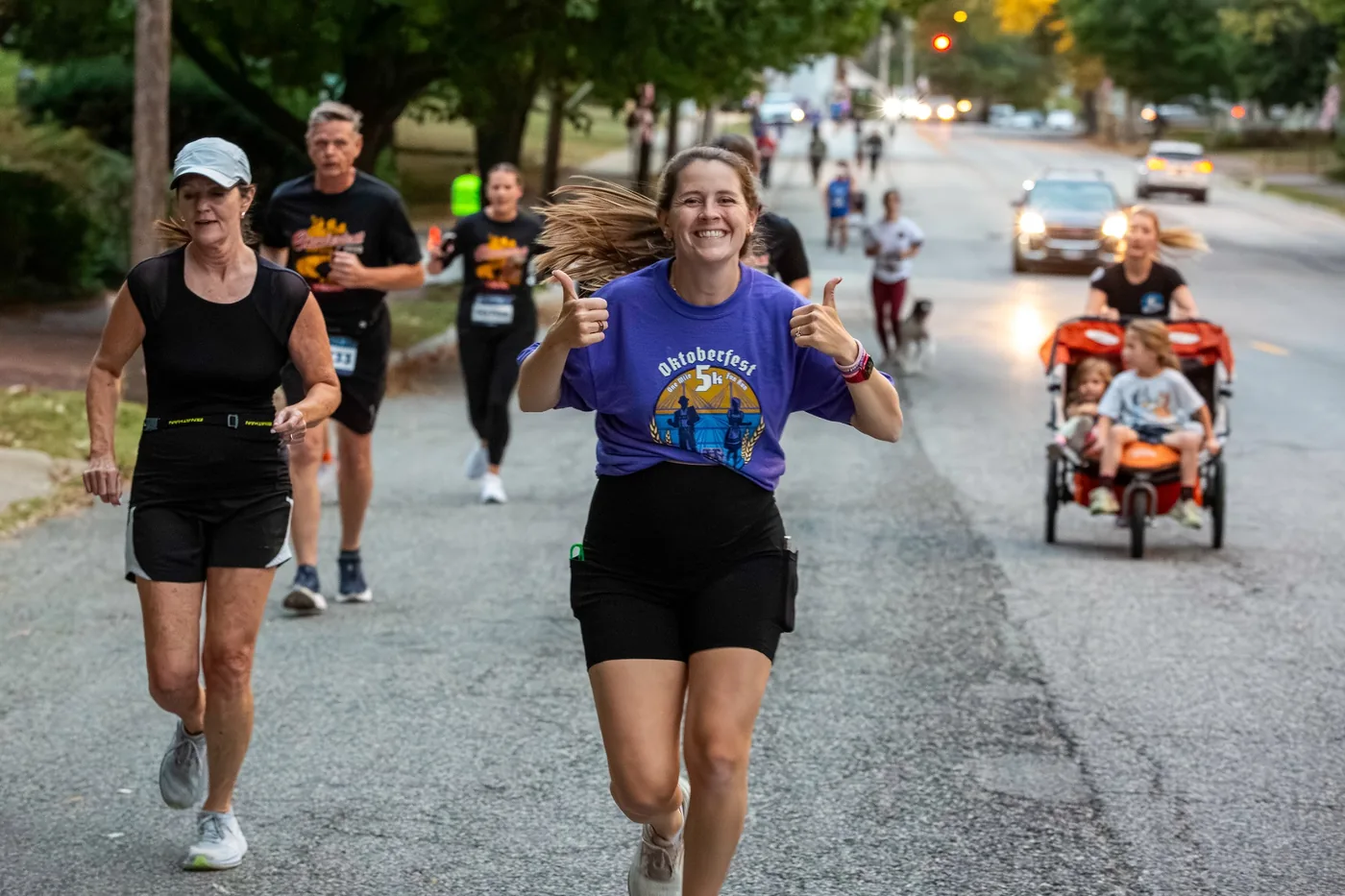Runner giving thumbs up with stroller teams nearby